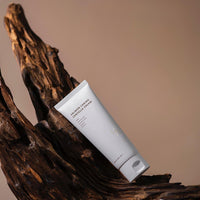 a tube of cream sitting on top of a wooden branch