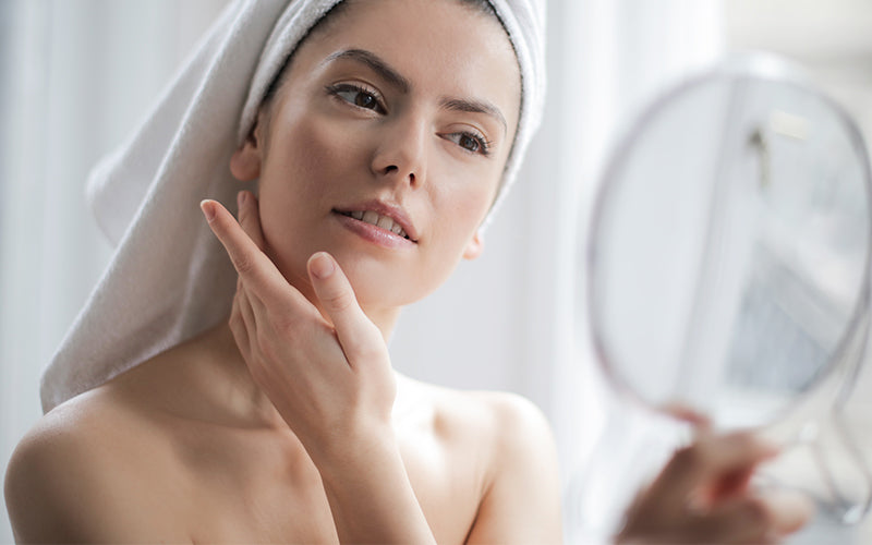 a woman with a towel on her head looking in a mirror